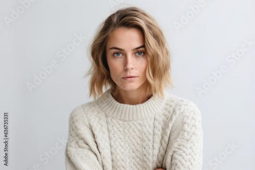 Portrait of a beautiful young girl in a white sweater on a white background.