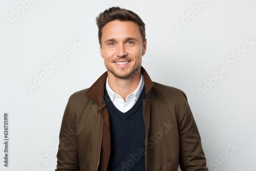 Portrait of handsome young man smiling at camera while standing against white background