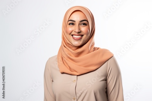 Portrait of a Saudi Arabian woman in her 30s in a white background wearing a smart pair of trousers