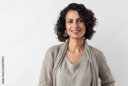Portrait of a Saudi Arabian woman in her 40s in a white background wearing a chic cardigan
