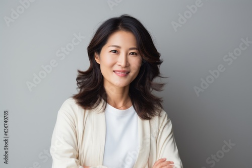 Portrait of a smiling asian woman looking at camera over gray background
