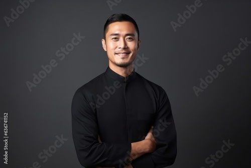 Portrait of a happy young asian man with arms crossed on black background