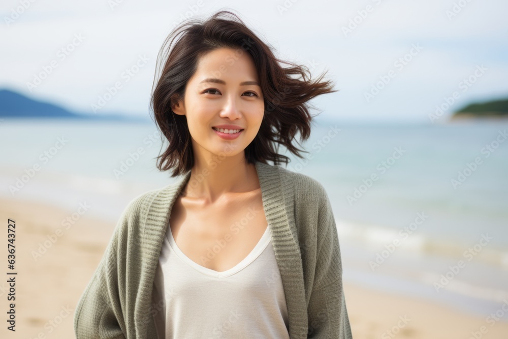 Portrait of a happy young woman standing on the beach and looking at camera Portrait of a happy young woman standing on the beach and looking at camera