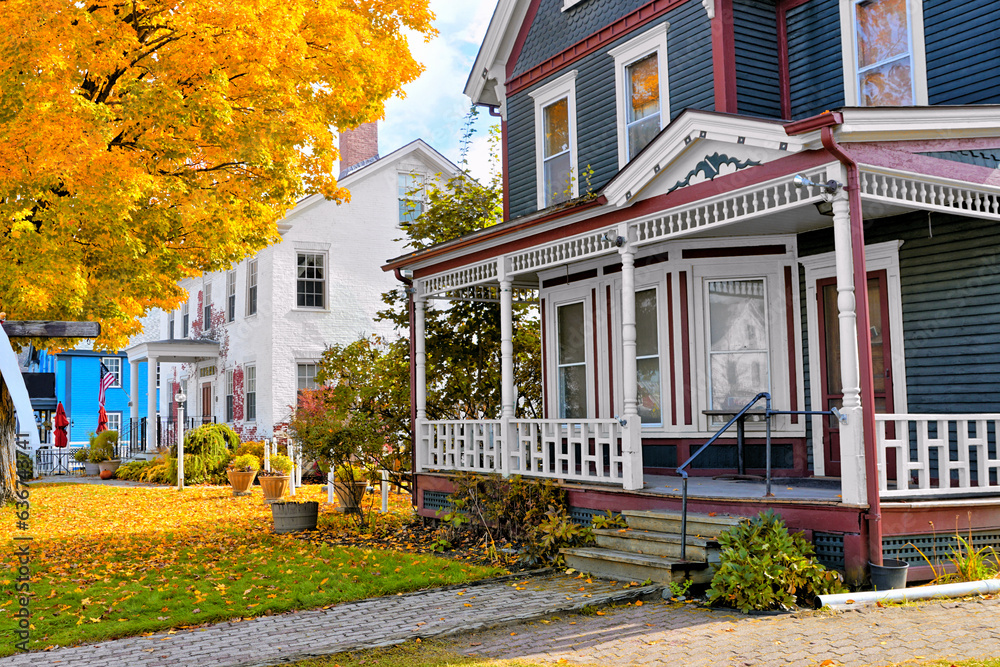 Beautiful rural houses with vibrant yellow maple tree during autumn in New England, USA