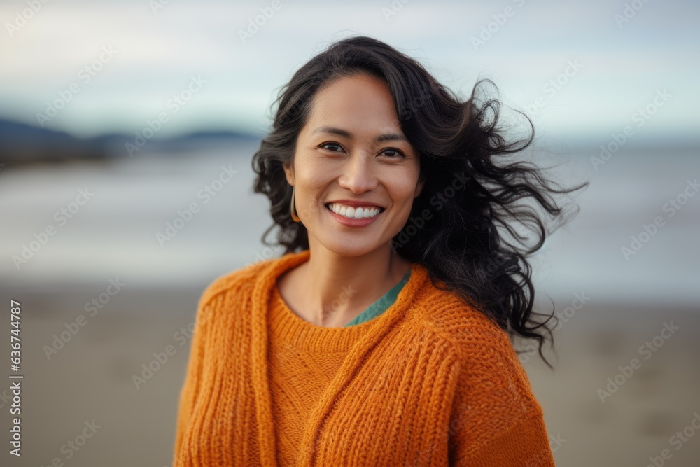 Portrait of a smiling young woman standing on the beach in autumn