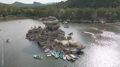 Boat trip on catamarans and boats.Stone island of Zhumbaktas in the middle of a mountain lake in Kazakhstan Borovoe.The rock in the middle of the water the Kazakh Sphinx.A lot of people on the water photo