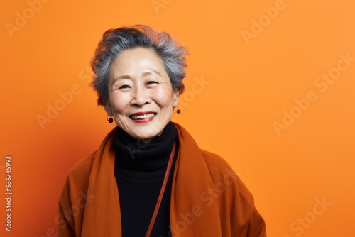 Portrait of a Chinese woman in her 70s in an abstract background wearing a chic cardigan