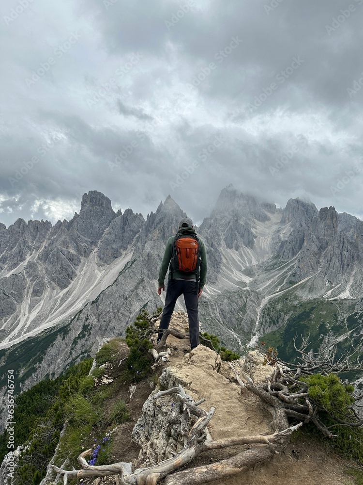 Obraz premium Adventurous hiker standing atop a mountain, looking out over the vast landscape below