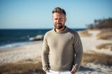 Portrait of a Russian man in his 40s in a beach background wearing a chic cardigan