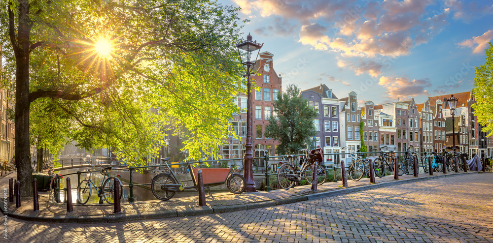 Heart of Amsterdam. Early morning in Amsterdam. Ancient houses, a bridge, traditional bicycles, canals and the sun shines through the trees. Great day in Amsterdam.