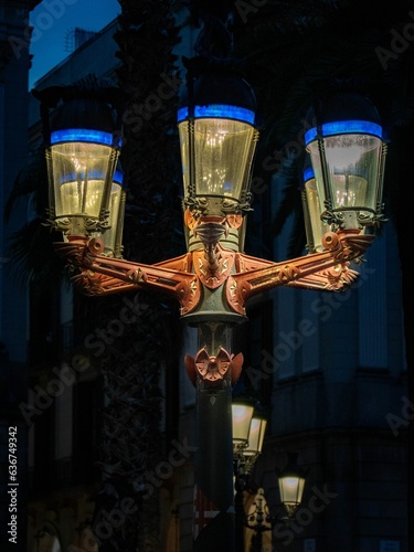 Vertical closeup of a vintage illuminated street light in the dark photo