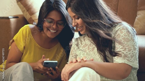 friends talking on something by watching something on phone and laughing