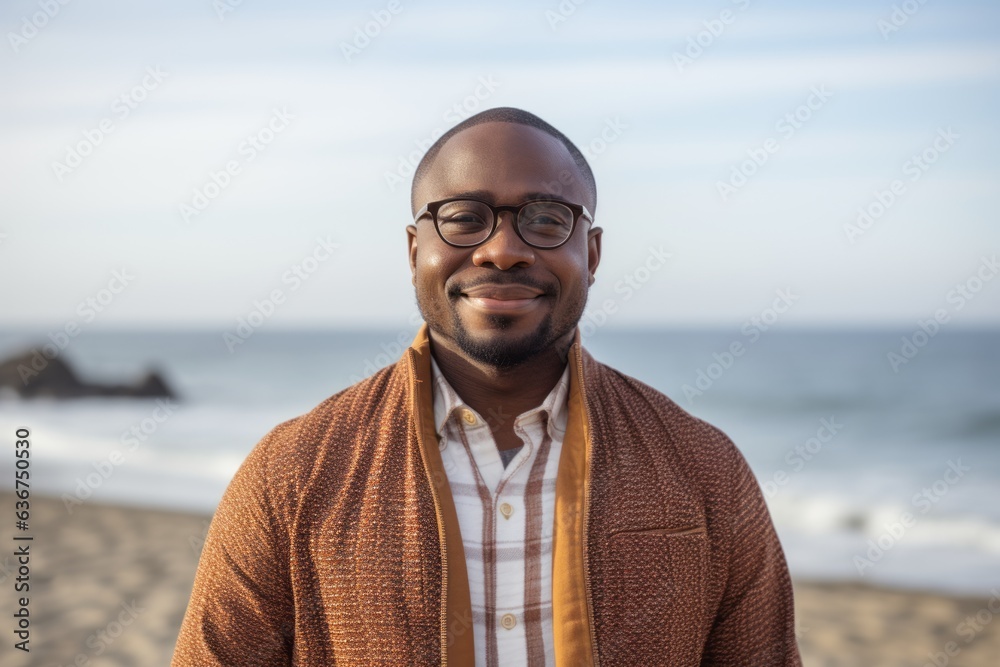 Portrait of smiling young man with eyeglasses standing on beach