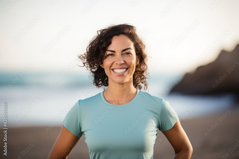 Portrait of smiling sporty woman standing on the beach at sunrise