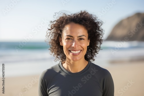 Portrait of smiling young woman with curly hair standing on the beach