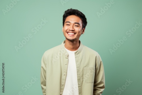 Portrait of a Indonesian man in his 20s in a pastel or soft colors background wearing a chic cardigan