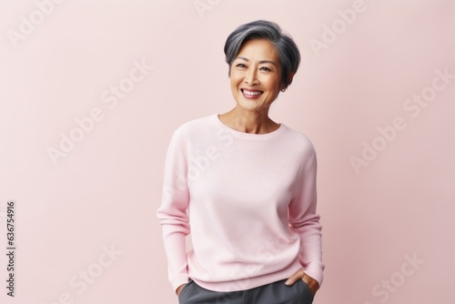 Portrait of a Indonesian woman in her 50s in a pastel or soft colors background wearing a cozy sweater
