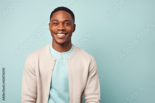 Portrait of a Nigerian man in his 20s in a pastel or soft colors background wearing a chic cardigan