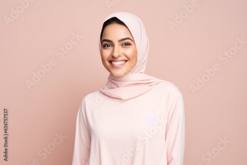 Portrait of a Saudi Arabian woman in her 30s in a pastel or soft colors background wearing a snuggly pajama set