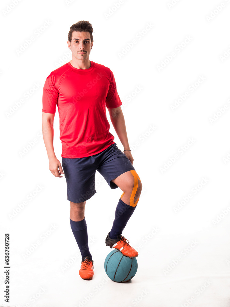 Photo of a man in a red shirt standing next to a blue ball in an isolated studio setting