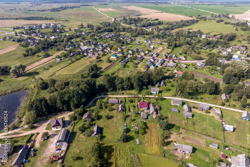 panoramic aerial view of eco village with wooden houses, gravel road, gardens and orchards