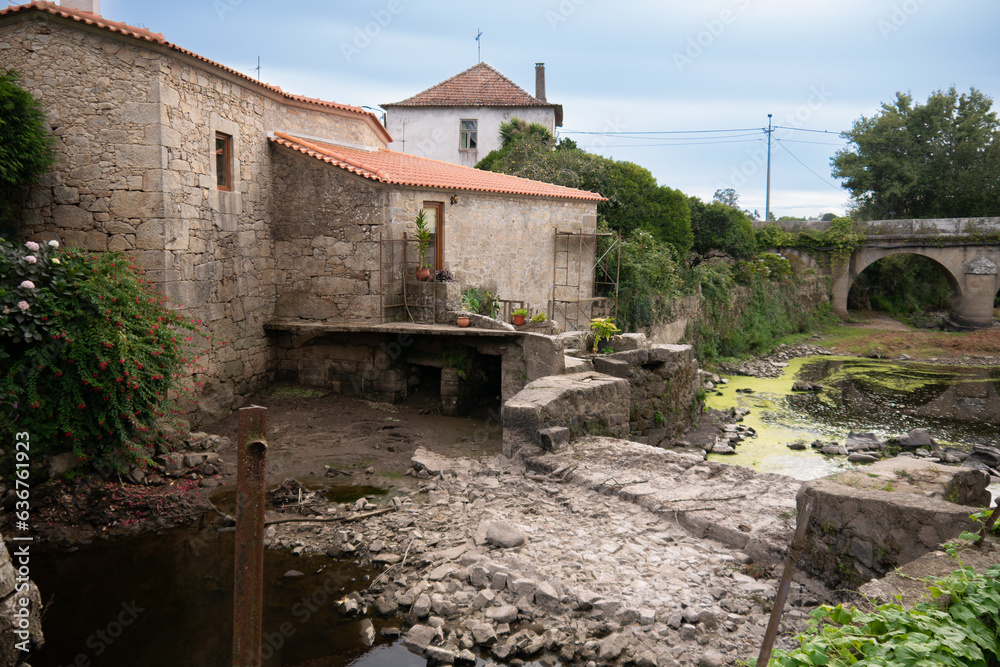 Dried up River Este in Portugal during drought in summer. Old stone mill buildings on bank.