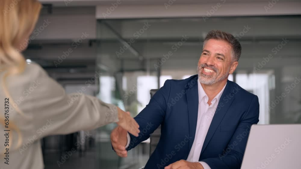Mature Latin business team of woman and European business man shaking hands as colleagues, partners or employees, signing a contract. Group of people satisfied with results of team work together. Mature Latin business team of woman and European business man shaking hands as colleagues, partners or employees, signing a contract. Group of people satisfied with results of team work together.