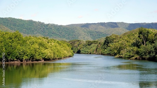 Aerial shot of a tranquil lake surrounded by lush greenery and hills in the background