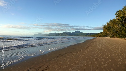 sand and waves wash up onto an empty beach with a view