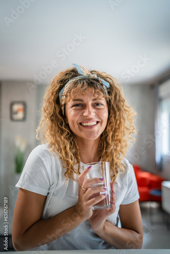 one adult caucasian woman sit at home hold glass of water happy smile