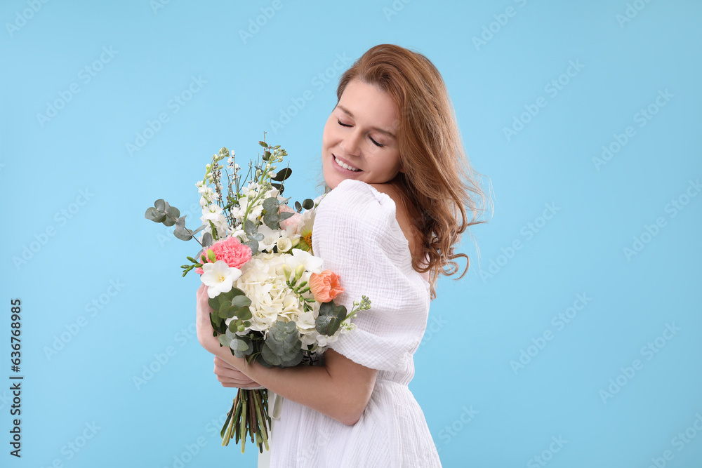 Beautiful woman with bouquet of flowers on light blue background