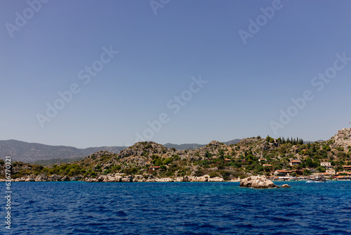 Fototapeta Naklejka Na Ścianę i Meble -  Beautiful view of the Mediterranean Sea with yachts. Picturesque landscape of blue ocean and green mountains on a sunny summer day. The sunken city of Kekova, Türkiye - 28 July 2023