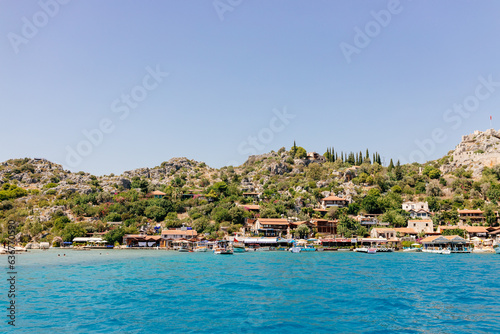Fototapeta Naklejka Na Ścianę i Meble -  Beautiful view of the Mediterranean Sea with yachts. Picturesque landscape of blue ocean and green mountains on a sunny summer day. The sunken city of Kekova, Türkiye - 28 July 2023