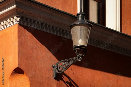 Vintage street lamp is affixed to the wall of an orange structure