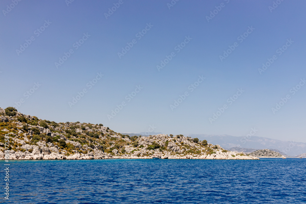 Beautiful view of the Mediterranean Sea with yachts. Picturesque landscape of blue ocean and green mountains on a sunny summer day. The sunken city of Kekova, Türkiye - 28 July 2023
