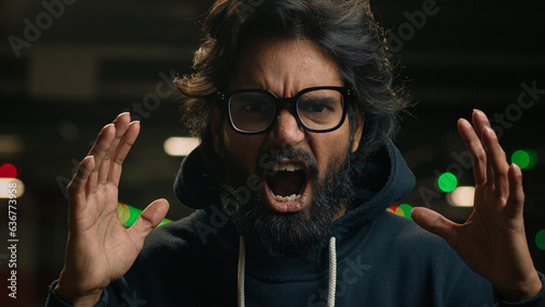 Fotografie Close up angry mad aggressive Arabian bearded man in glasses scream at dark park