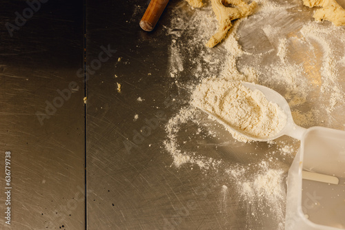 Принти на полотні Flour scoop sits on floury bakery table with dough scraps and rolling pin in pro