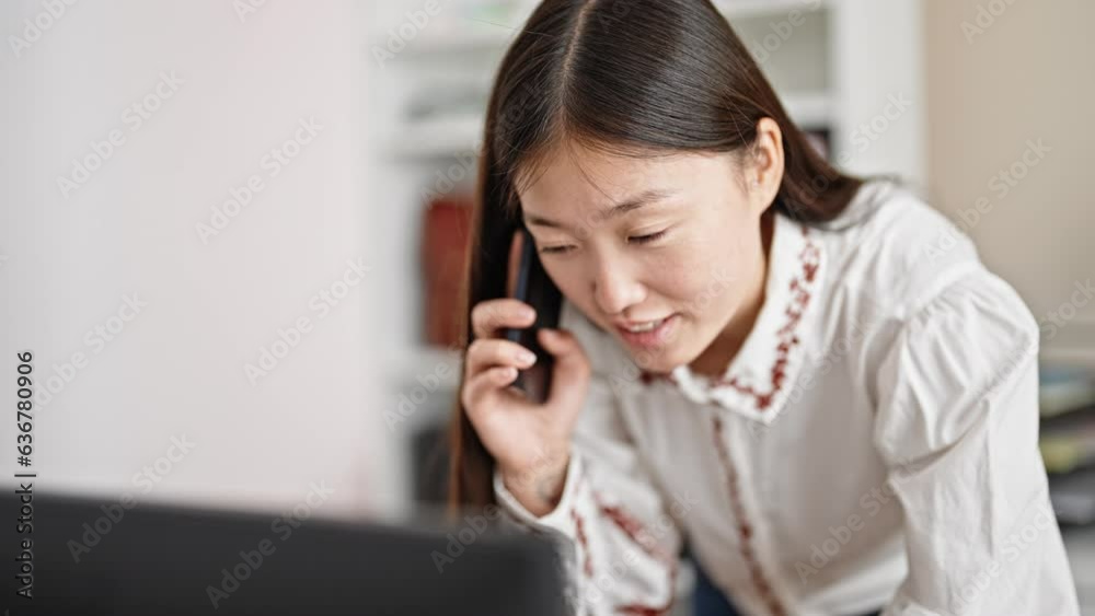Young chinese woman business worker using computer talking on smartphone at office Young chinese woman business worker using computer talking on smartphone at office