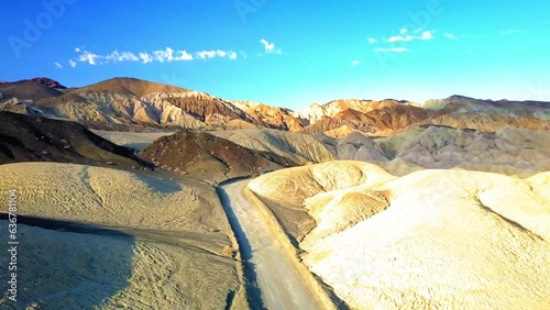 Aerial Upward Shot Of Road Amidst Rock Formations At Desert Against Sky, Drone Flying Backward Over Landscape On Sunny Day - Death Valley, California