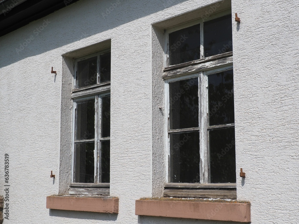 Closeup of an old wooden lattice windows in the house wall with peeling paint,