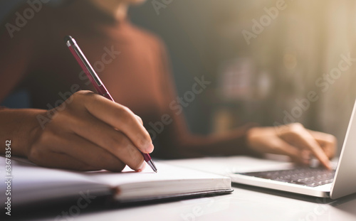 Woman hands using pen to list orders and sell products online and use Laptop typing on keyboard.