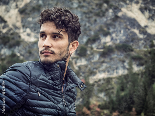 Photo of a stylish man with curly hair wearing a black jacket against the stunning backdrop of the Dolomites in Italy