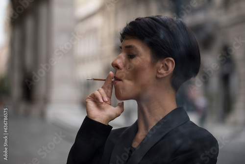 Fotografie Portrait of beautiful young girl in black dress with smoking cigarette