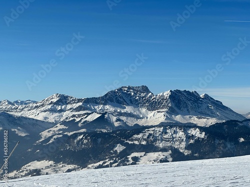 Mesmerizing landscape of a snowy field on the background of mountains on a sunny day