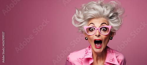 Surprised Mature Woman with Glasses with Big Hair on an Pink Background with Space for Copy