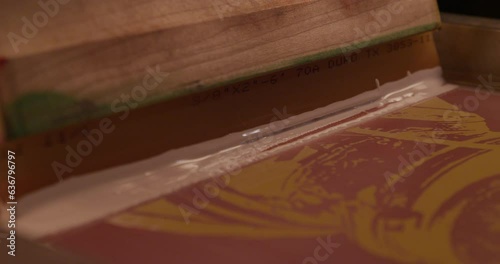 Rack focus of a screen and squeegee setup for tee shirt screen printing