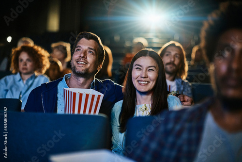 Young couple watching a movie and eating popcorn in a movie theater photo