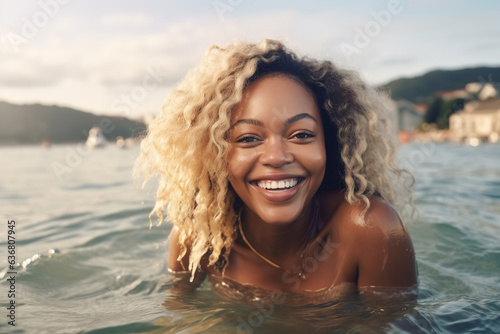 Young black woman swimming in sea. Blonde hair, smiling. Summer Europe vacation