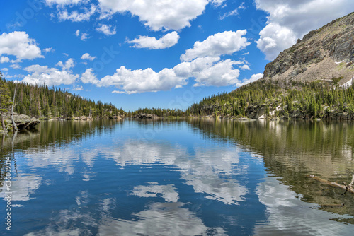 The Loch - A sunny Summer day view of blue sky and white clouds reflecting in calm mountain lake - The Loch, as seen from the west end of the lake towards to its east outlet. RMNP, CO, USA.