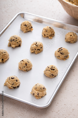 Chocolate chip cookie dough scoopes on a cookie sheet ready to be baked